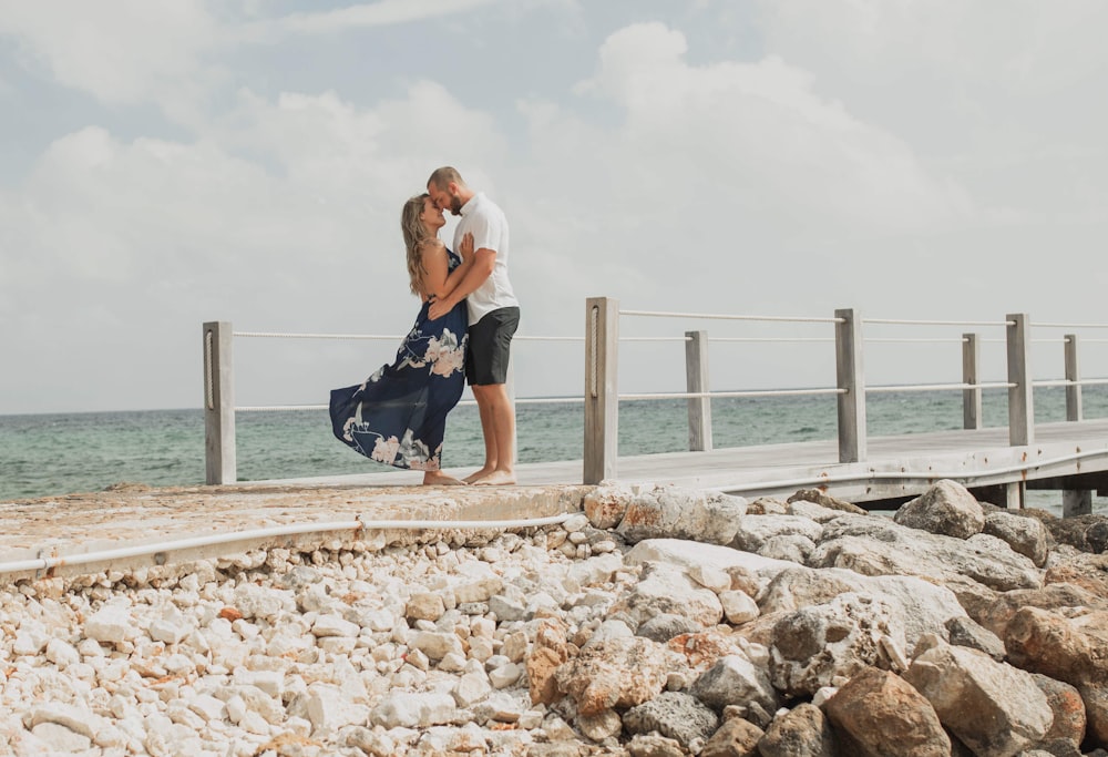 man and woman kissing each other beside seashore during daytime