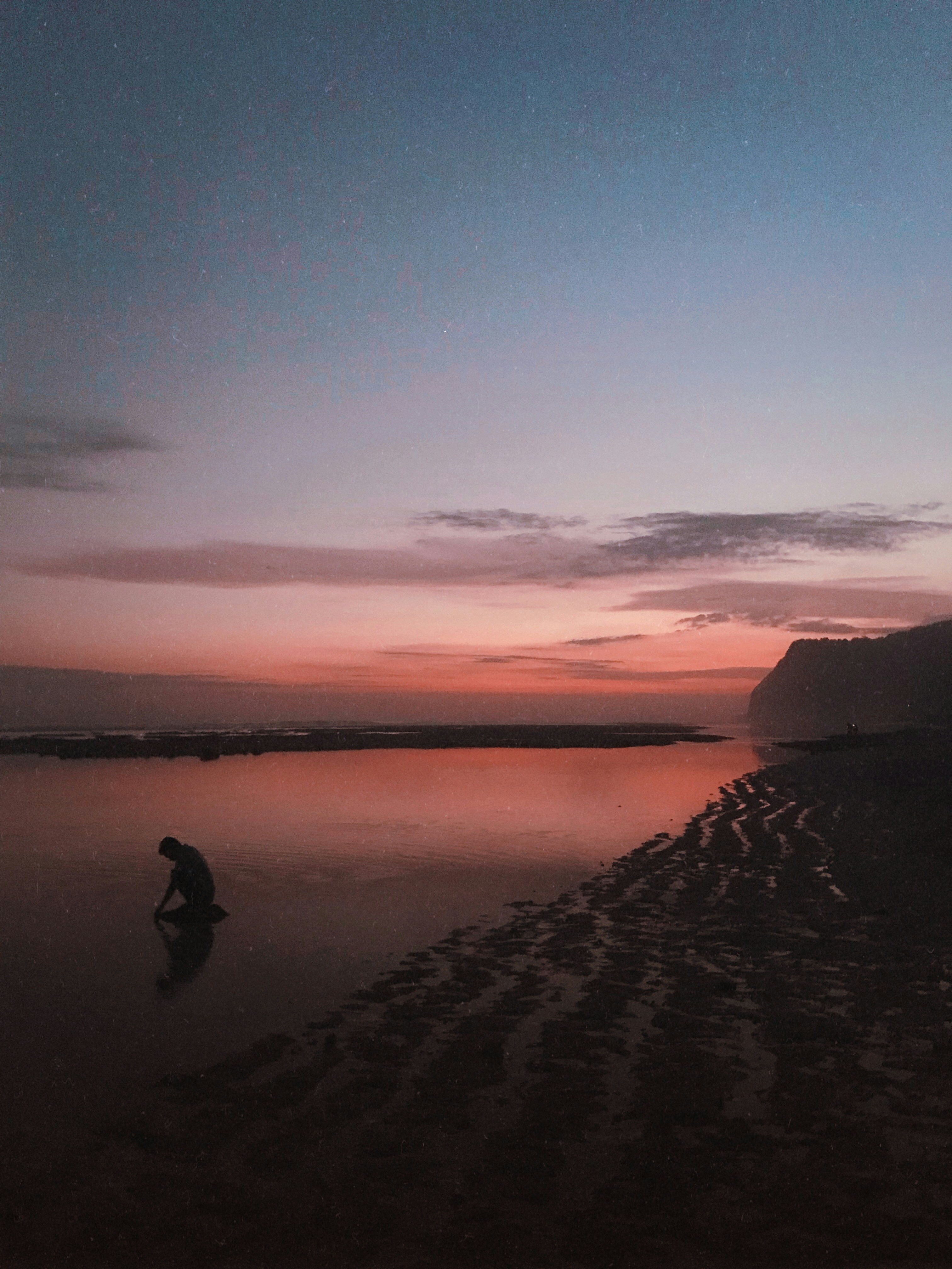 silhouette of person near body of water during daytime