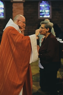 woman kneels while receiving the body of Christ during mass