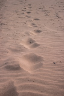 A close-up of footprints in soft sand, symbolizing small steps forward.