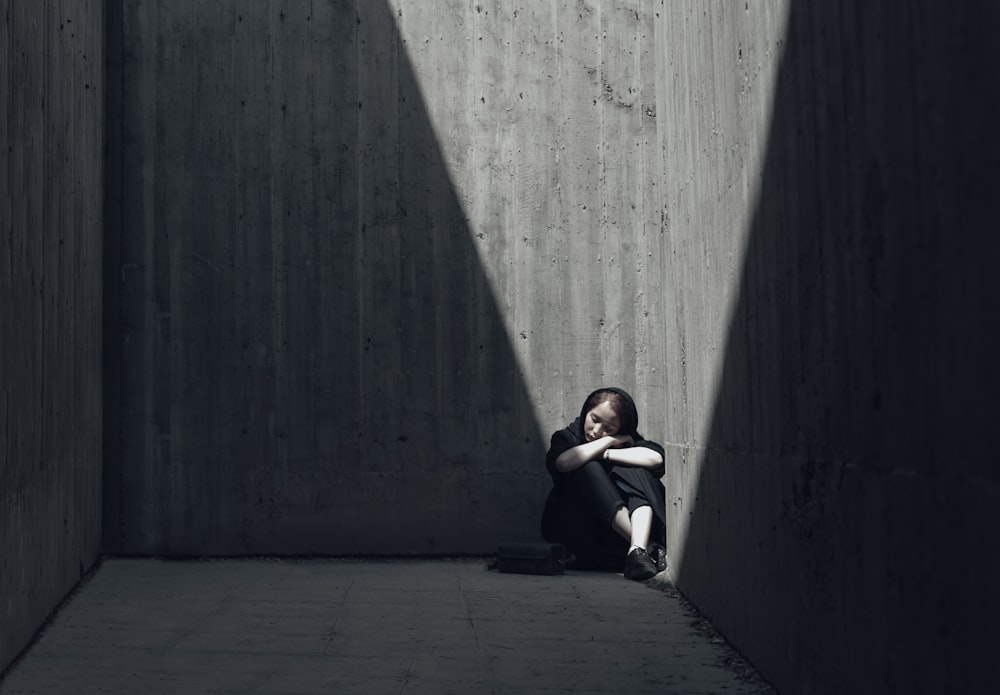 grayscale photo of woman sitting on corner