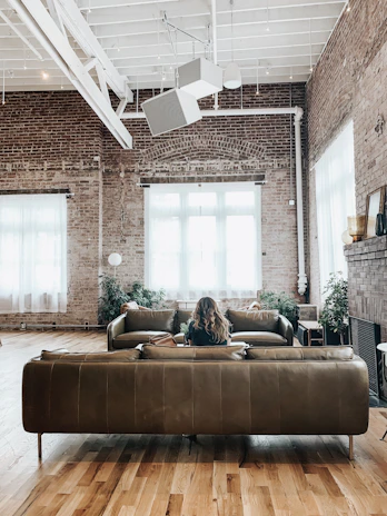 Intimate view of a renovated loft living area featuring exposed brick walls, rich hardwood floors, and large industrial windows letting in natural light.