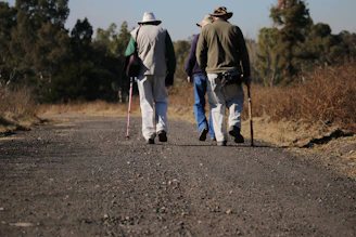 three people walking road during daytime