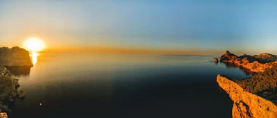 A panoramic sea view from the hotel balcony during sunset, casting golden hues.