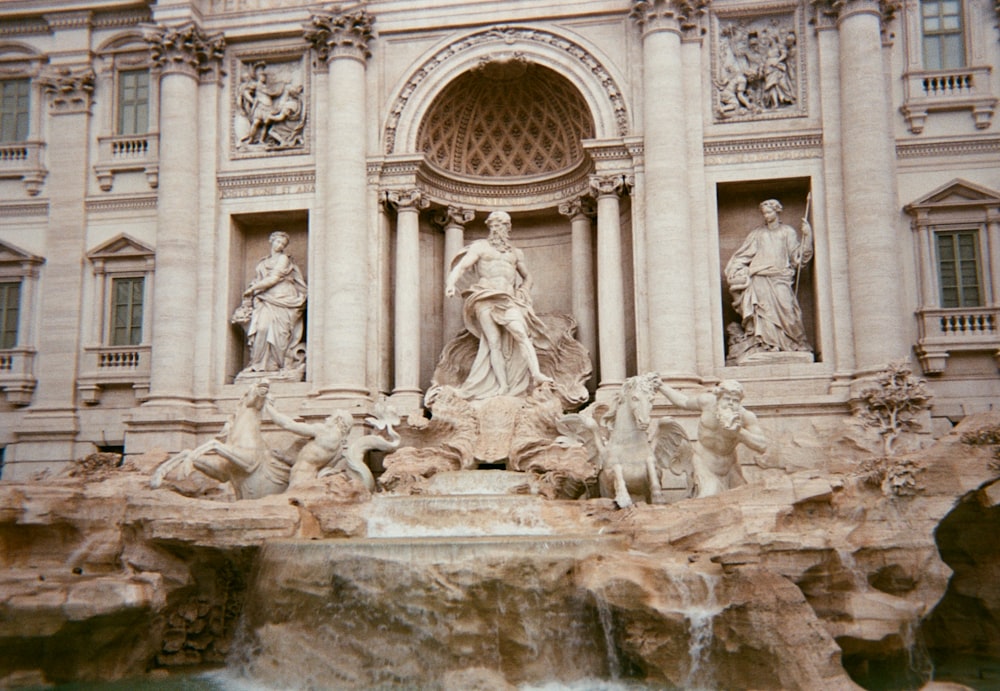 a fountain in front of a building with statues on it