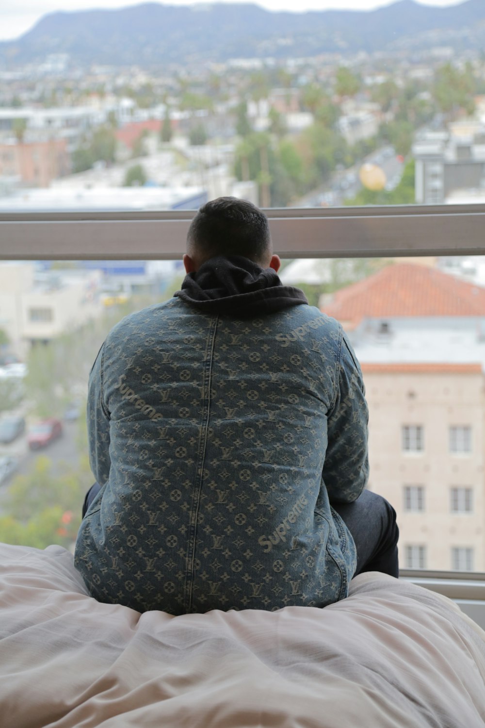 uomo che indossa una camicia grigia seduta sul letto