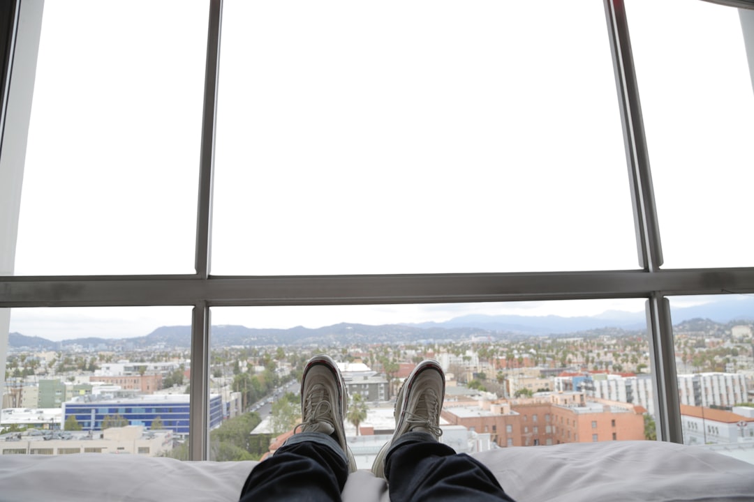 man lying on bed wearing black pants and white sneakers, Sitting in LA