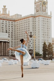 ballerina dancing near white concrete building during daytime