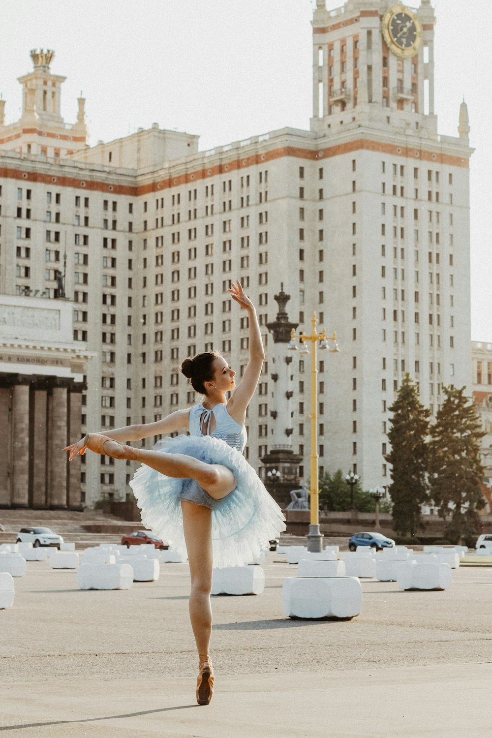 Ballerina tanzt tagsüber in der Nähe eines weißen Betongebäudes