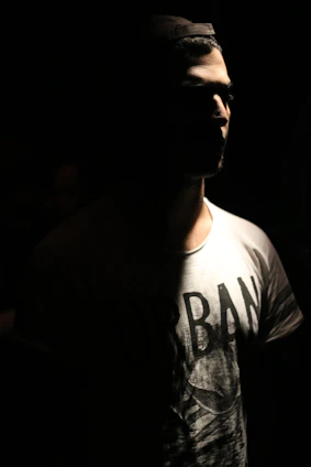 Black and white urban scene with a model wearing s-reign, highlighting fabric texture and embroidered logo under subtle neon lights.