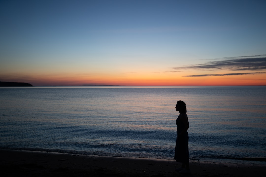 silhouette photography unknown person standing near body of water