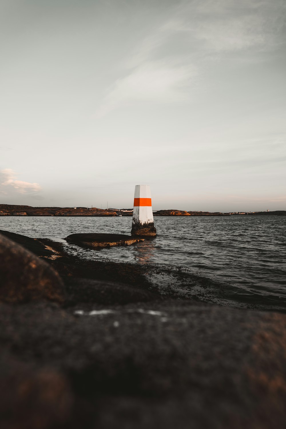 white and orange buoy floating in the sea