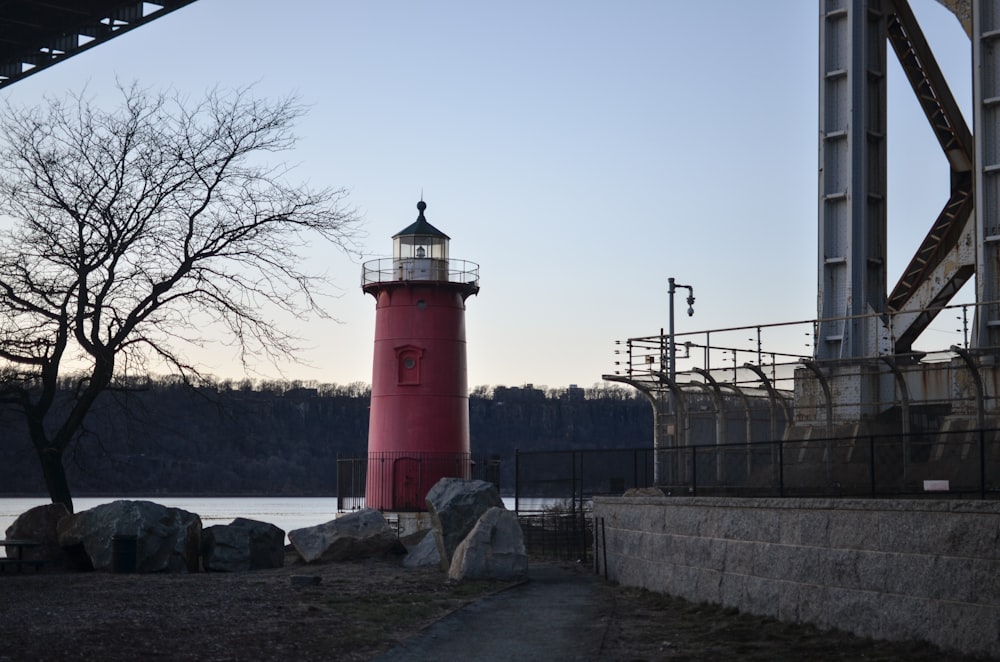 a red light house next to a body of water