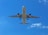 A commercial airplane is flying overhead against a bright blue sky with a few scattered clouds. The photograph captures the underbelly of the aircraft with its landing gear extended.