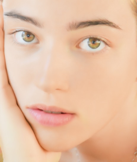 A serene photo of a person gently touching their face, highlighting subtle facial symmetry in soft natural light.