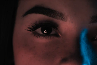 Close-up of a human eye reflecting cosmic symbols and light.