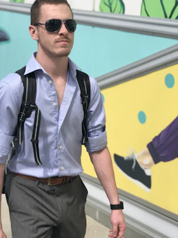 A man wearing a stylish backpack walking confidently through a city street.