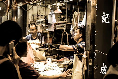 Close-up of hands exchanging goods and money in a lively market environment.