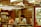 A traditional apothecary setting with two people engaged in discussion or transaction. Wooden drawers line the wall, indicating storage for herbs or medicines. The environment is warm and reflects the style of an old-world herbal medicine shop.