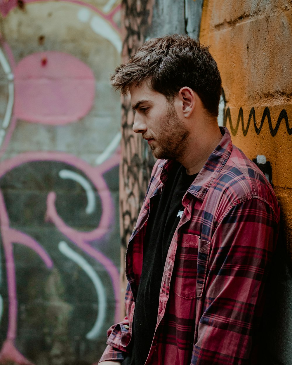 man leaning on brown wall