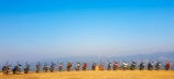 A panoramic shot of bmck motorcycles lined up on a mountain overlook at sunset.