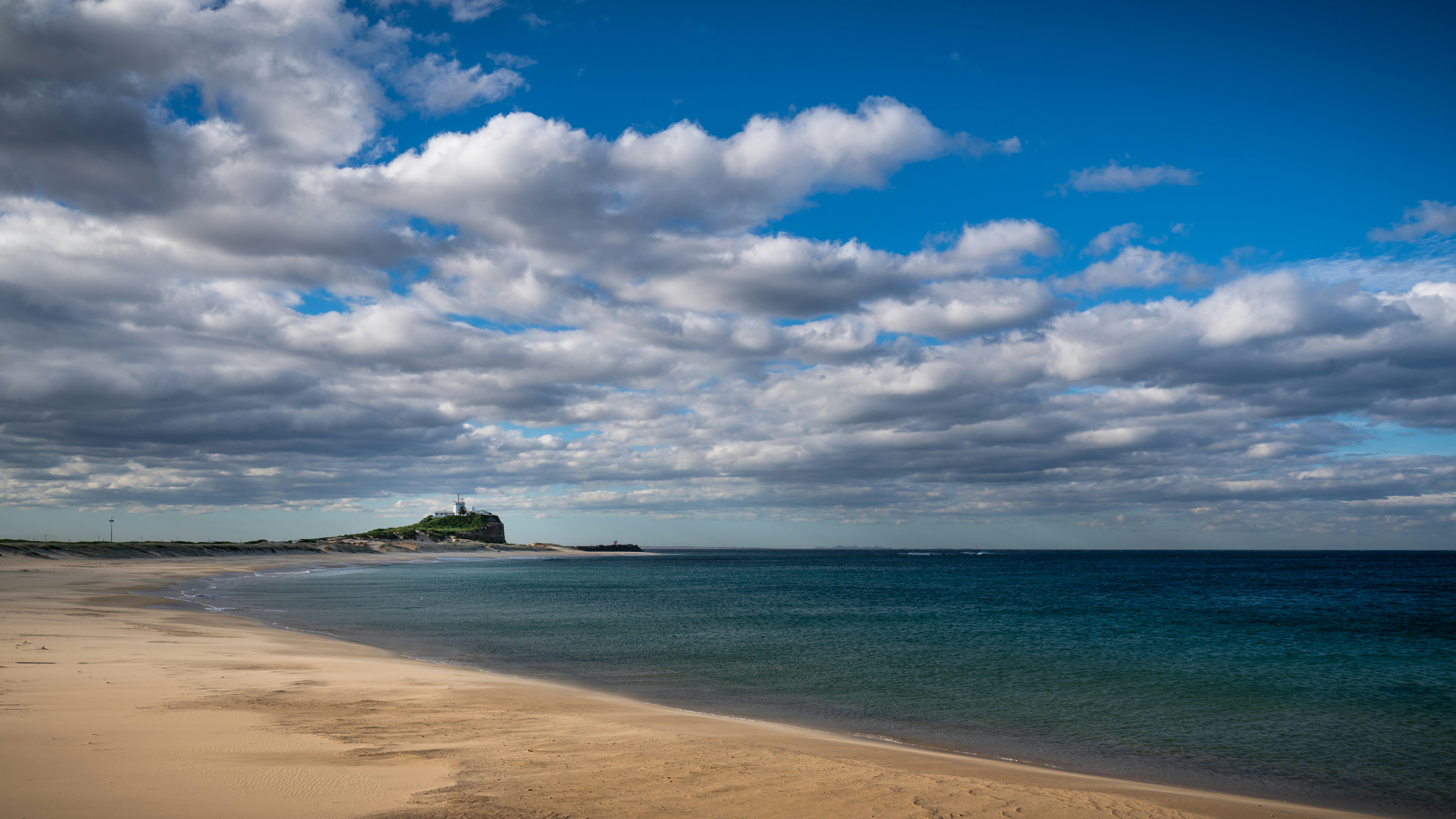 a sandy beach next to the ocean under a cloudy sky