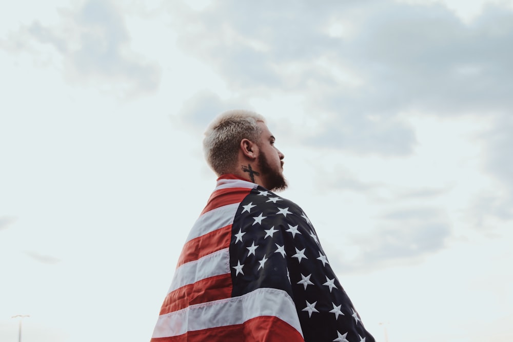 shallow focus photo of man wearing flag of USA under cloudy sky during daytime