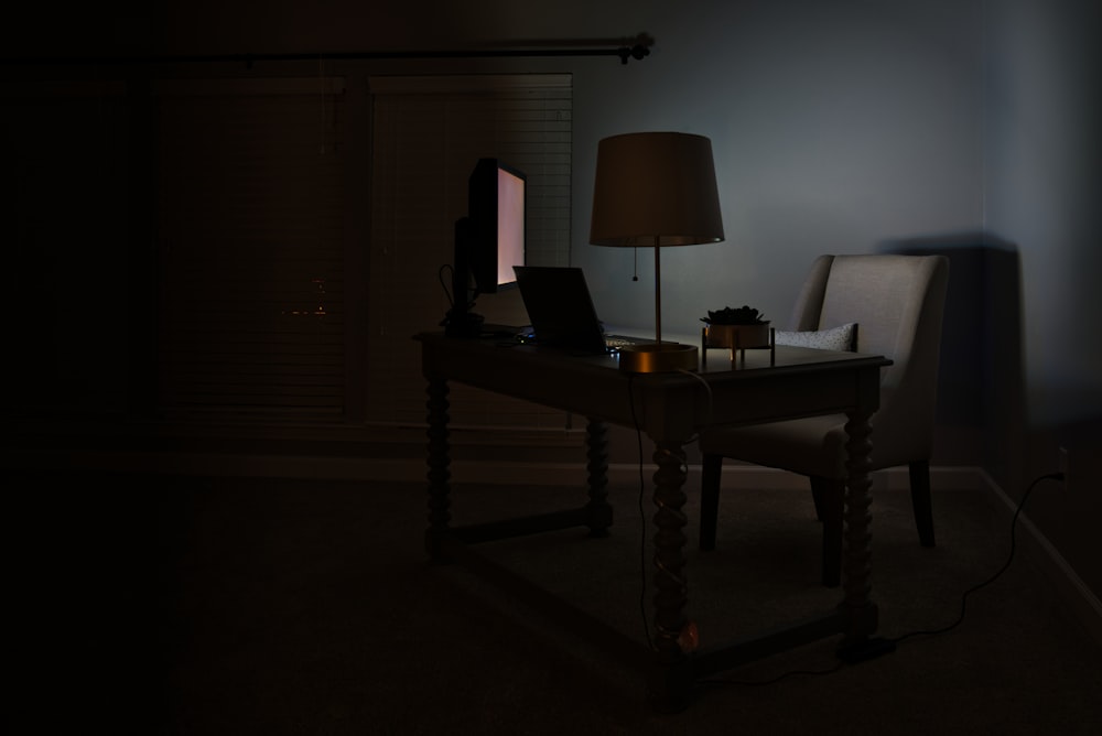 a desk with a lamp and a laptop on it