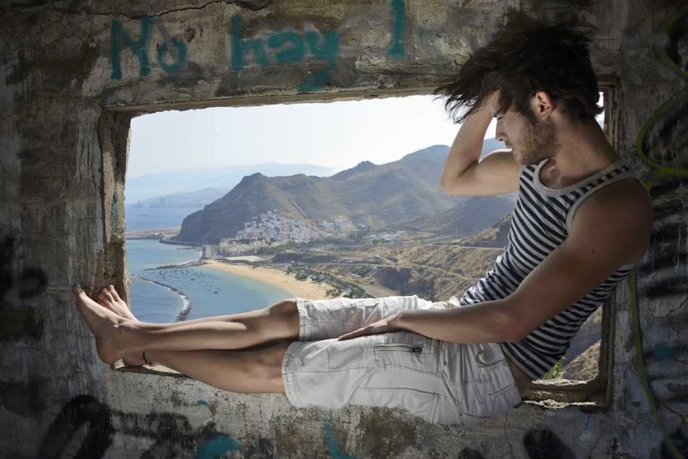 man sitting on window during daytime