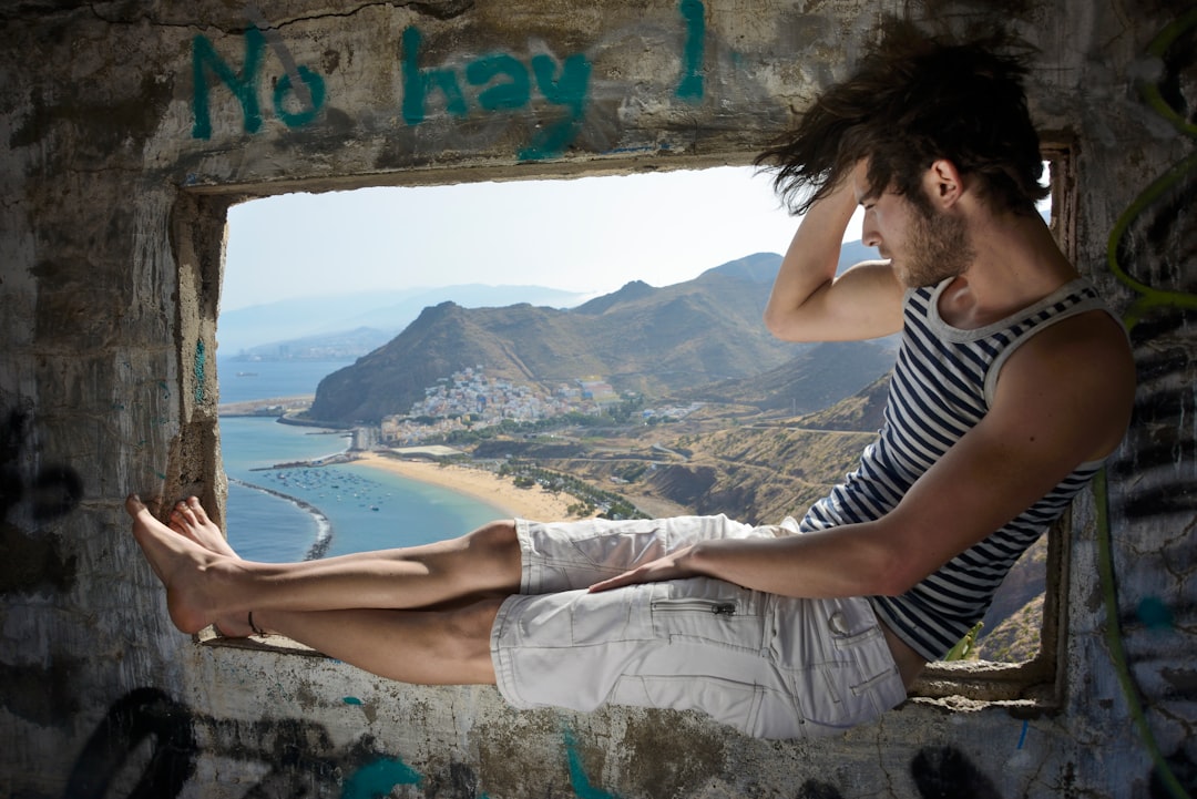 man sitting on window during daytime