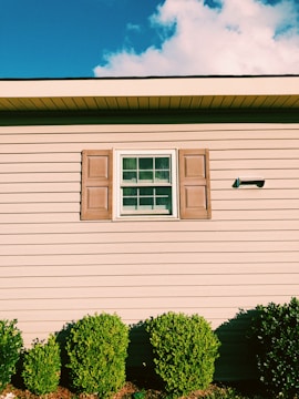A charming Toronto house with a newly painted beige exterior and dark green shutters under a clear sky.
