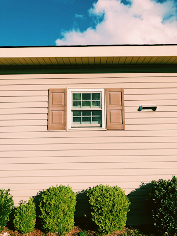 A bright, freshly painted exterior house wall in navy blue with crisp white trim under a sunny sky.