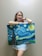 A smiling woman holding a watercolor painting by Shanthi.