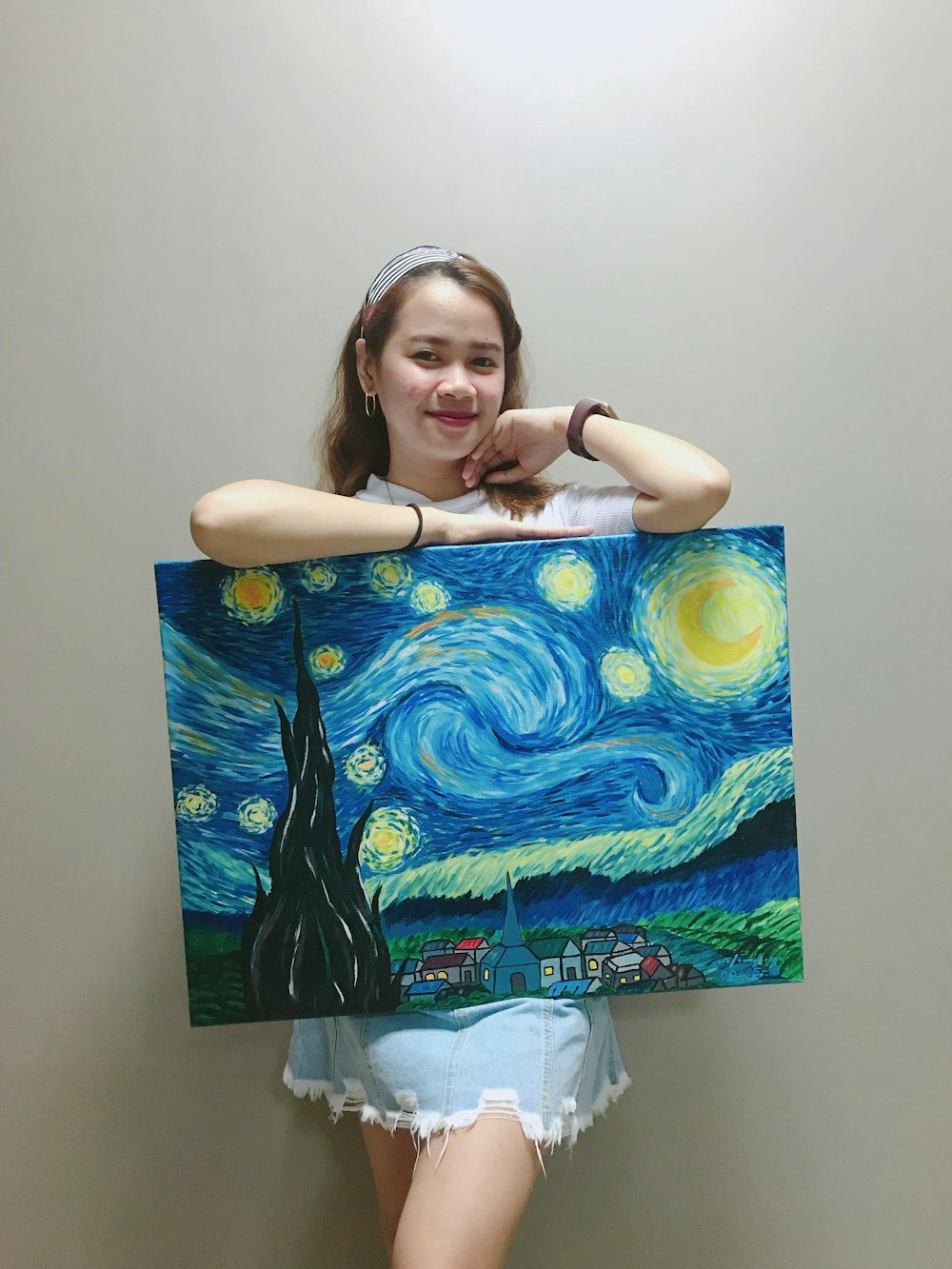 mujer sonriente de pie y sosteniendo la pintura de la noche estrellada de Vincent Van Gogh