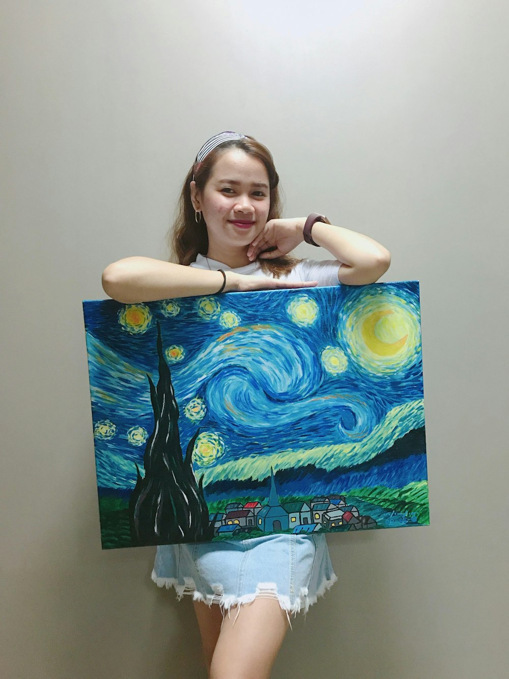 smiling woman standing and holding Starry Night painting by Vincent Van Gogh