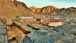 Restored ancient fort walls blending with the desert landscape under a golden sunset.