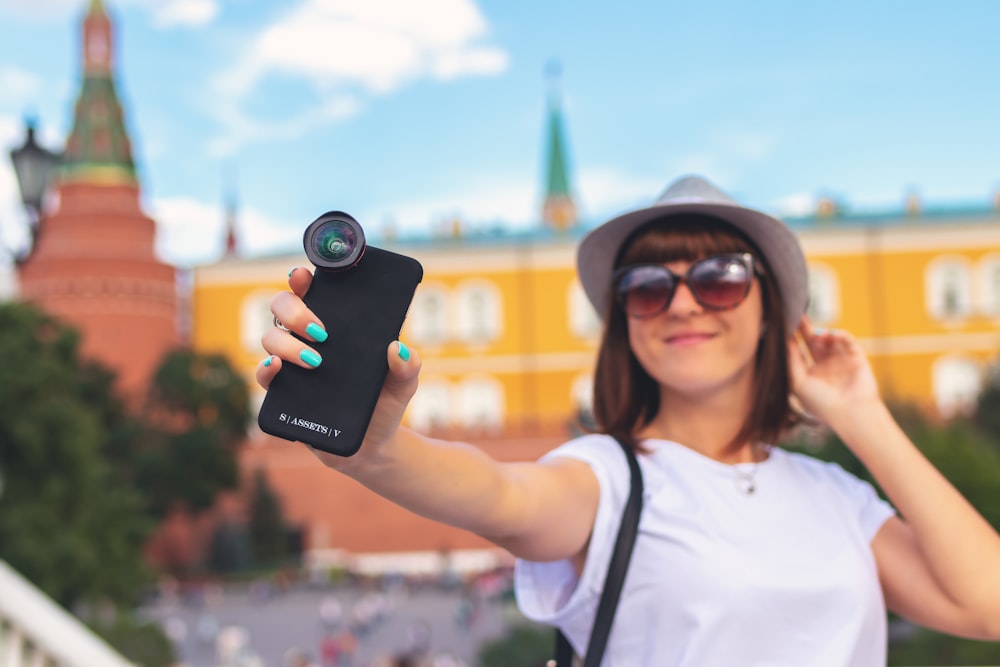 Mujer sosteniendo un teléfono inteligente con lente de clip