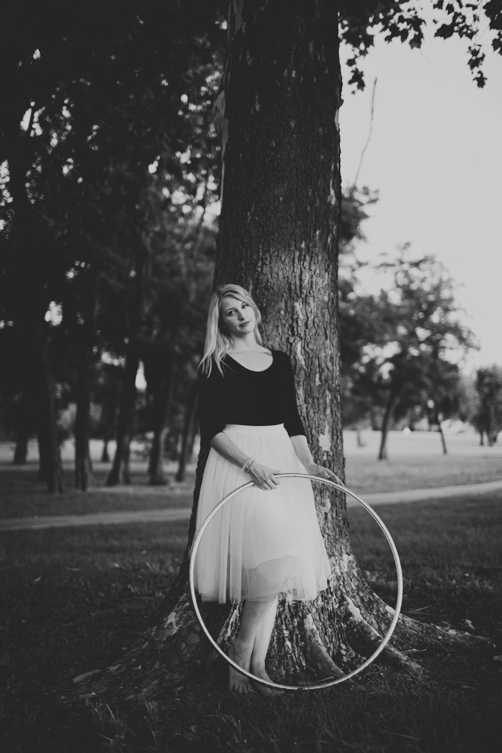 woman standing beside tree holding hula hoop