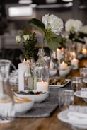 selective focus photography of white flowers beside lighted candle on table