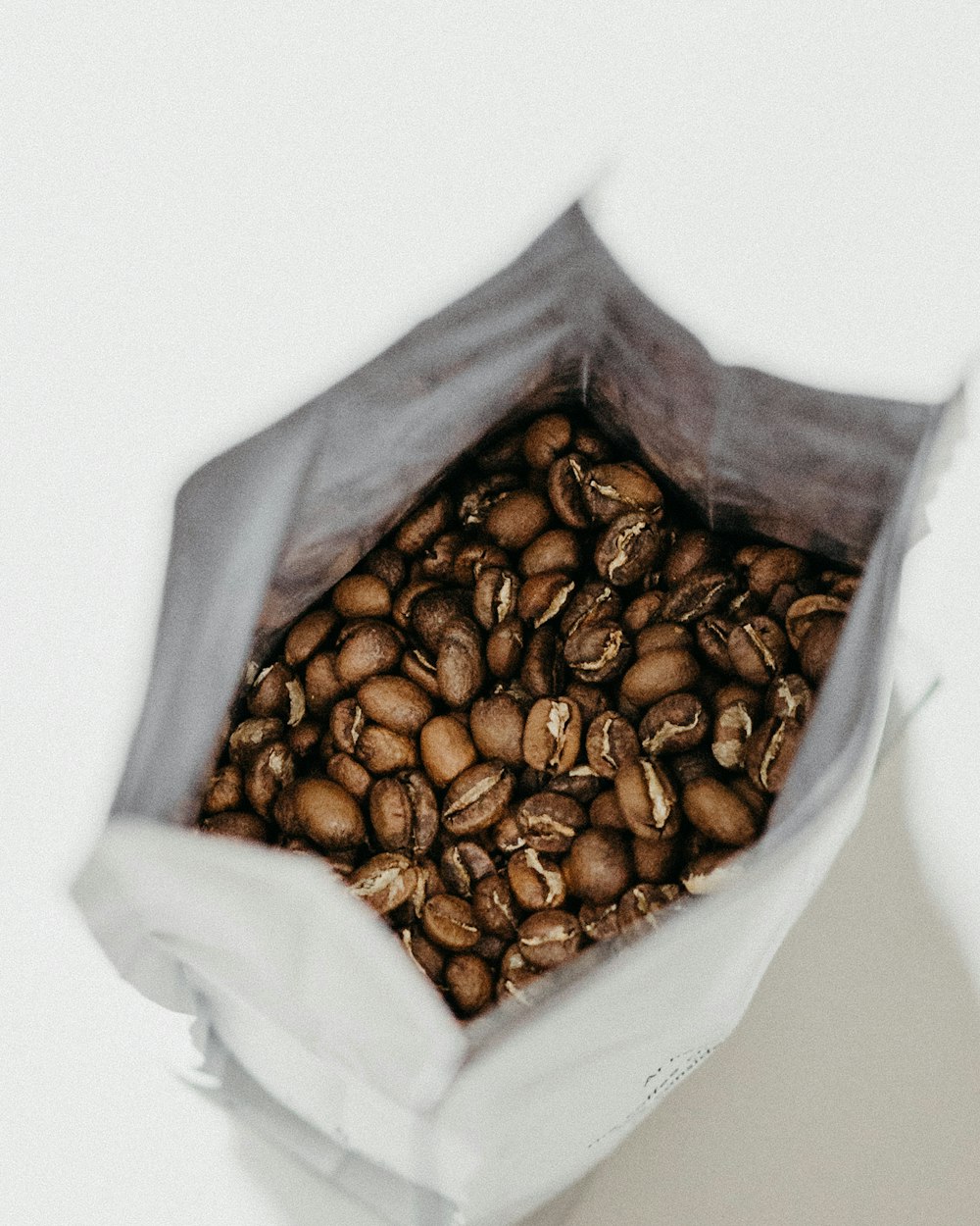 grains de café bruns à l’intérieur d’un sac blanc