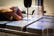 person drilling metal bar