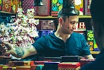 man wearing gray shirt standing inside with girl dolls and boxes