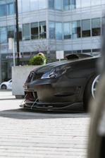 Close-up of a sleek front splitter on a black Ford Mustang in an urban setting.