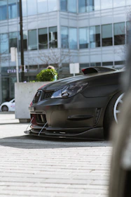 Close-up of a sleek front splitter on a black Ford Mustang in an urban setting.