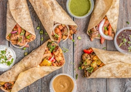 A colorful spread of wraps, sandwiches, and mocktails on a rustic wooden table.