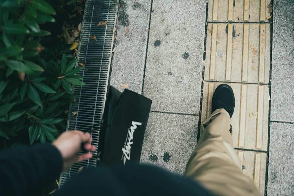 person carrying shopping bag while walking on pavement