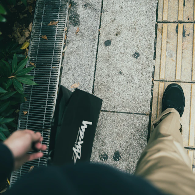 A person carrying a shopping bag while walking along a city pavement