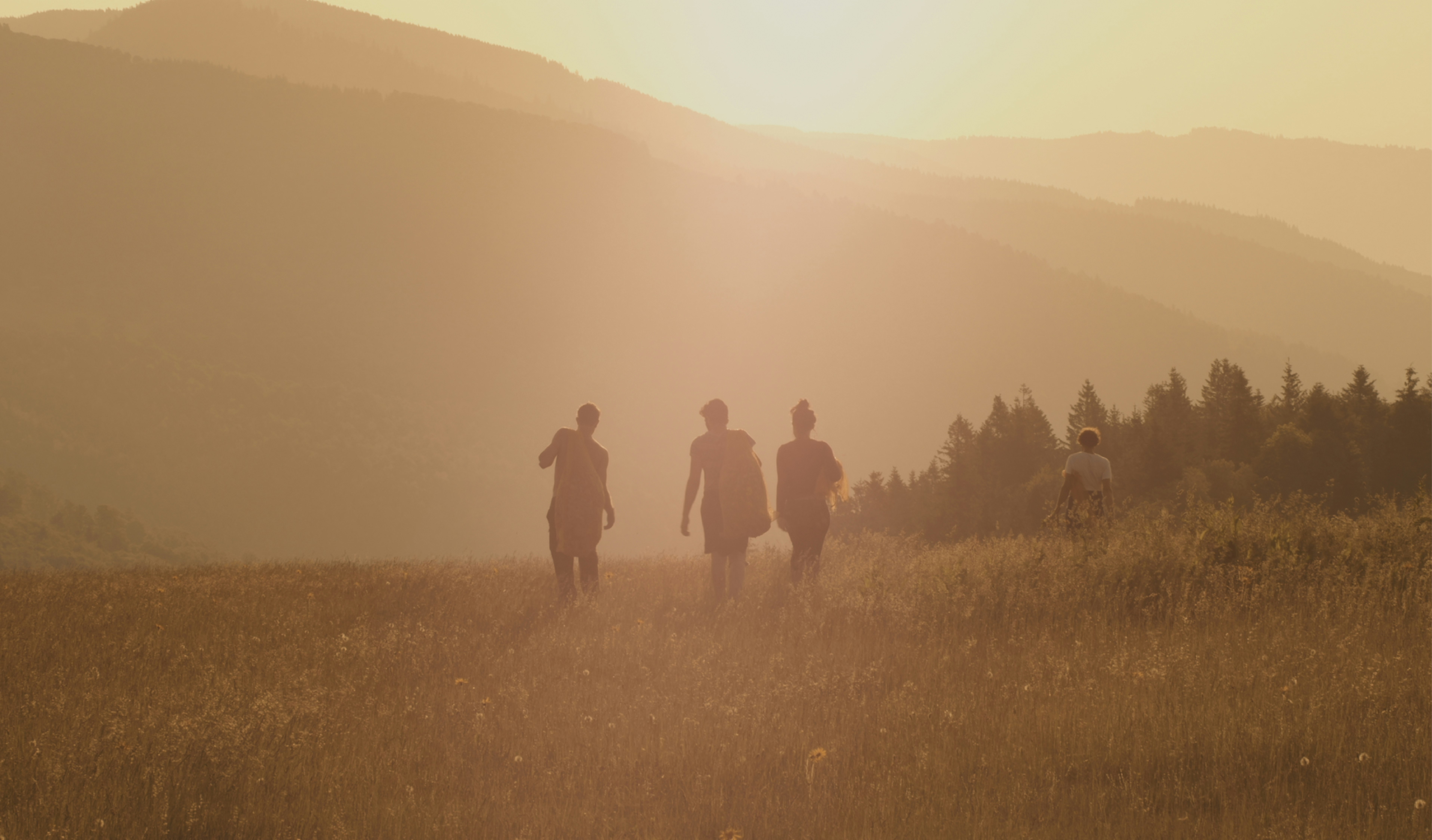 three people walking on brown fields during daytime
