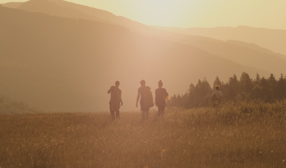 three people walking on brown fields during daytime