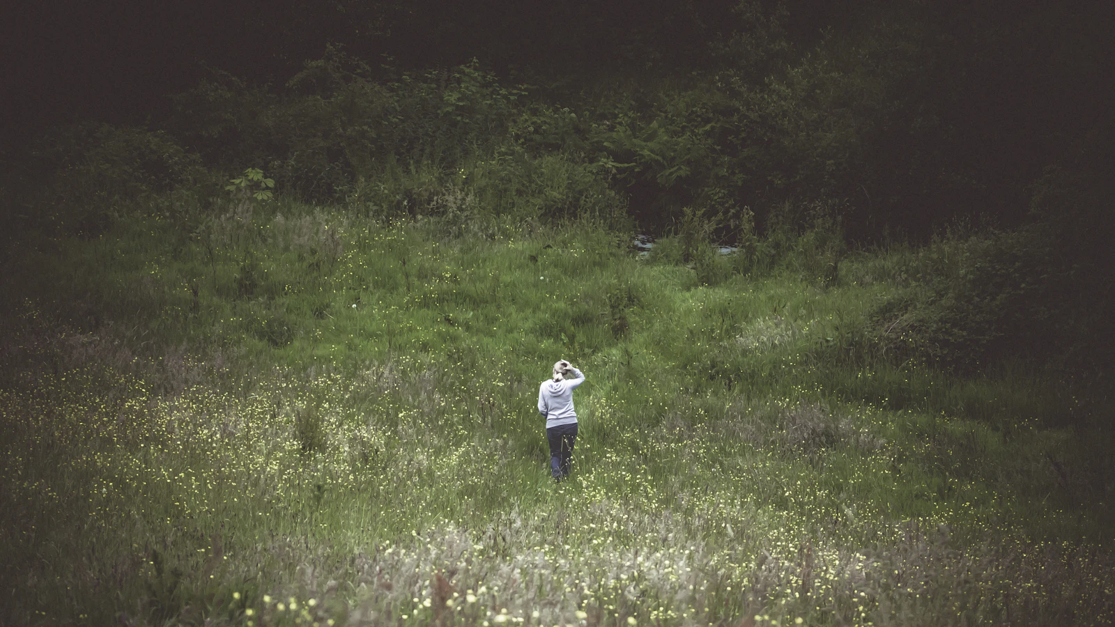 woman standing in an open green field